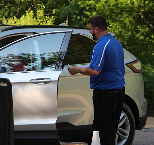 A male valet attendant getting in a car to park it